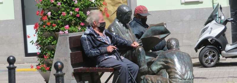 Vecinos de Telde con mascarillas sentados junto a la escultura El betunero, en la plaza de Los Llanos/TA.